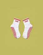 White BADDIE Pilates grip socks with red varsity stripes and heart-shaped non-slip grips by CHEEKYBEEN